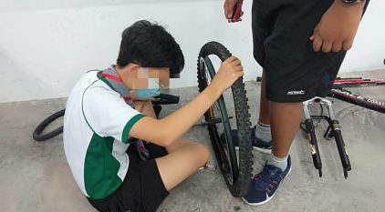 2 people working on fixing a bicycle wheel/tyre