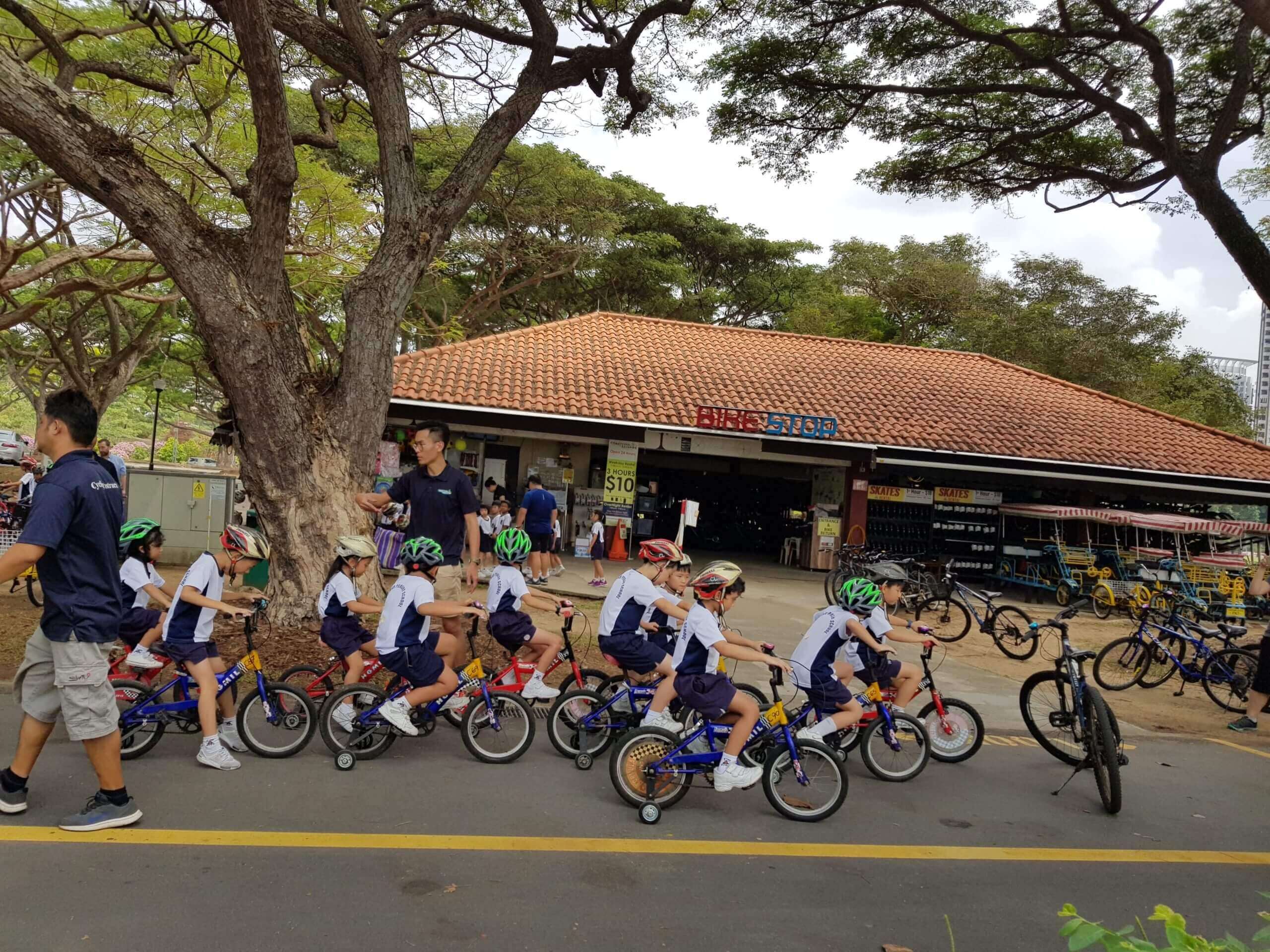 A group of school children riding a bike with guidance from adult trainer