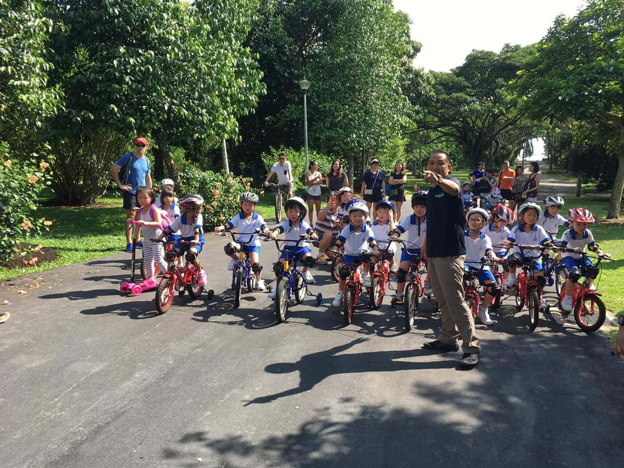 A group of young children riding a bike with guidance from adult trainers