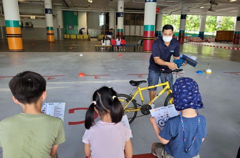 Adult teaching 3 children about bicycles